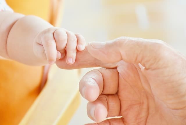 La mano de Bebé con la mano del padre